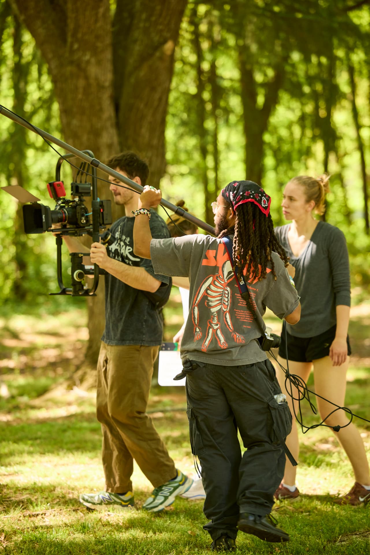 Crew carrying camera and boom equipment through the trees